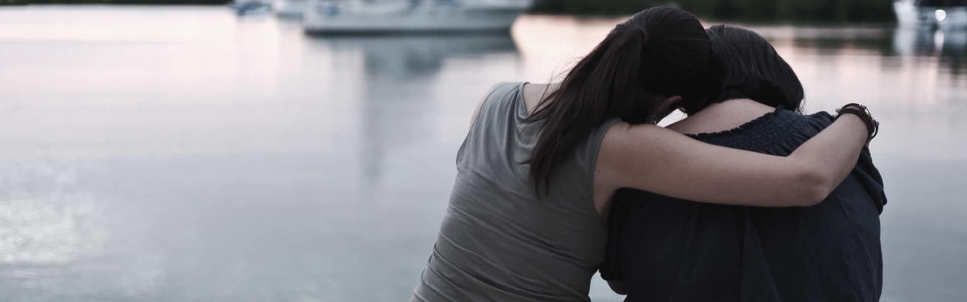 woman comforting friend by the water